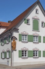 Blue sky, pointed gable house with green shutters and bishop figure, Kisslegg, Allgäu,