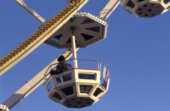 A geometric gondola of a Ferris wheel against a clear blue sky at an amusement park