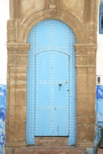 An ancient blue door with an ornate stone archway, featuring a weathered look in a historical