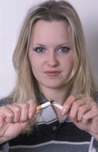 A woman breaks a cigarette in half, symbolizing quitting smoking with a determined look
