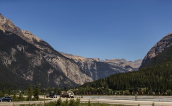 Mountain pass with highway and vehicles, surrounded by forest as viewed from the Trans Canada
