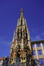 Gothic fountain, richly decorated, rises proudly under a bright blue sky, Nuremberg, Middle