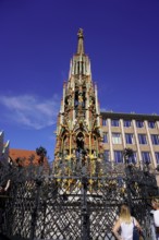 Detailed Gothic fountain with colourful decoration in front of a clear blue sky, Nuremberg, Middle