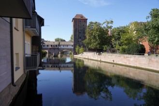 Picturesque river view with old buildings and bridge, peaceful atmosphere under blue sky,