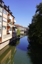 View of a river between buildings and a bridge under a bright blue sky, Nuremberg, Middle
