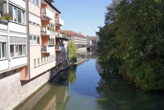 Quiet river between buildings and trees with a bridge in the background, Nuremberg, Middle