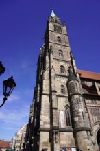 Gothic church tower made of sandstone, rises in front of a bright blue sky, Church of St. Lawrence,