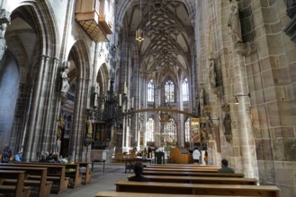Large church room with pews and Gothic architecture, visited by people, Church of St. Lawrence,