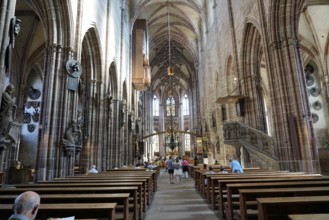 Nave with high vaults, benches and people inside a historic church, Church of St. Lawrence,