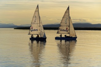 Lake Neusiedl, Burgenland, Austria, Europe, Two sailboats at dusk with mountains on the horizon and