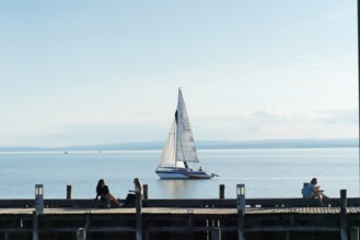 Lake Neusiedl, Burgenland, Austria, Europe, A sailboat sails calmly on a lake while people relax on