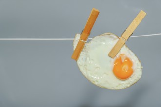 Clothespins holding a fried egg on a clothesline, representing a creative food concept