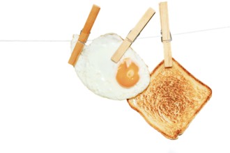 Clothespins holding fried egg and toast on clothesline create unusual breakfast image