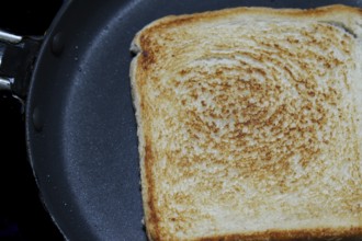 Close-up of a single slice of toasted white bread in a frying pan, showing the texture and