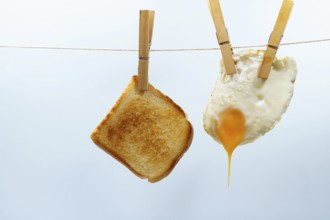 Toast and fried egg hanging from a clothesline with clothespins, representing a simple and