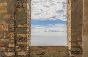 Sunny mediterranean sea scenery seen through a window opening in a historic wall seen in Liguria,