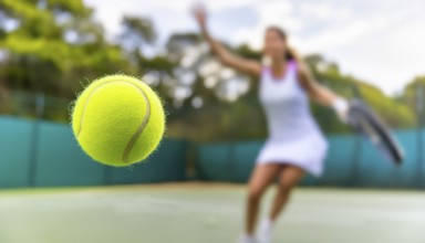 AI generated image showing a flying tennis ball closeup and female player in court ambiance