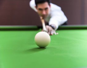 AI generated image showing a billiards table closeup with player and cue ball