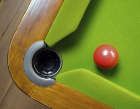 AI generated image showing a billiards table closeup with ball and pocket seen from above