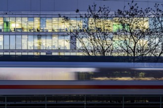 Office building at night. In front of it a passing ICE train of Deutsche Bahn AG. Stuttgart,