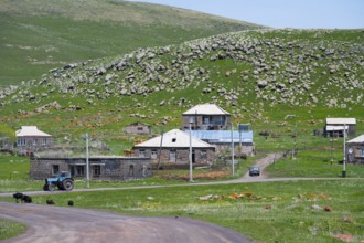 Rural houses on a hillside with a tractor on a road, surrounded by green nature, Zorakert, Lake