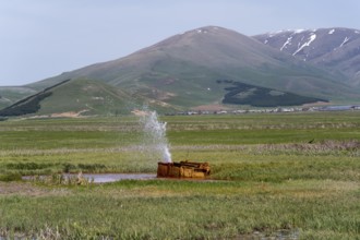A tranquil landscape with hills and a water fountain in a green meadow, geyser near Karmravan,