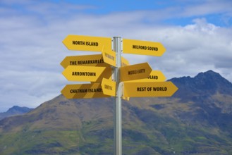Yellow signpost in a mountain landscape, showing directions to different places, Queenstown,