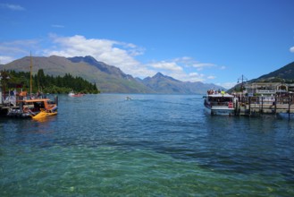 Boats on a jetty with a view of the surrounding mountains and blue water, Queenstown,