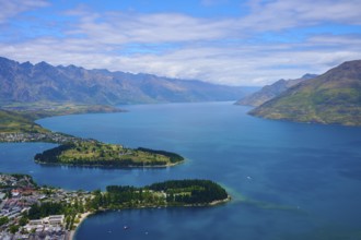 Expansive panorama of a large lake surrounded by mountains and clouds in the sky, Queenstown,