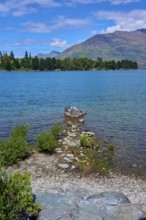 Rocks on the shore of a lake with mountains in the background and a clear atmosphere, Queenstown,