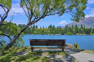 Idyllic landscape with bench and view of a lake and mountains in the background, Queenstown,