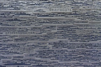 Large number of ship silhouettes on grey metal plate with German texts on ship types, naval