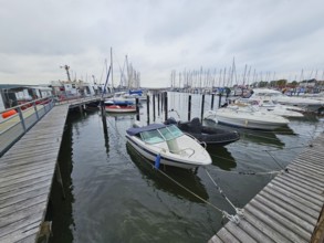 Several motorboats are moored in a harbour, surrounded by jetties and under an overcast sky, Laboe,
