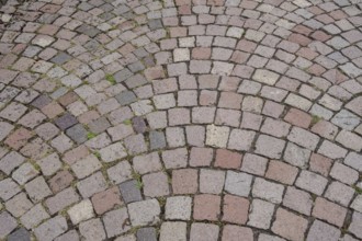 Floor covering made of paving stones with an arched pattern in grey and reddish tones, background,