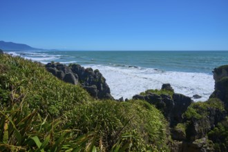 Panoramic view of the coastline with cliffs and ocean under a bright blue sky, Pancake Rocks,