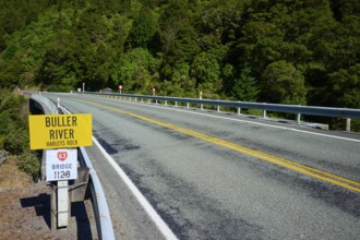 Road leads over bridge at Buller River, surrounded by forest and traffic signs, Buller River,