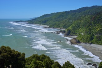 Long coastline with green hills and gentle waves under a clear blue sky, West Coast, South Island,