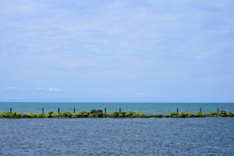 View of the sea with a row of rocks and calm blue sky, Mana Bay, Patea, Taranaki, North Island, New