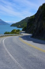 Narrow, winding road meanders along a lake through mountain landscape, Devil's Staircase Lookout
