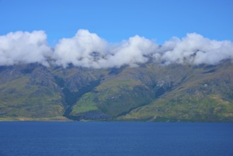 Mountains with a wreath of clouds over a blue lake under a clear sky, Drift Bay, Lake Wakatipu,