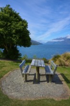 Single picnic table overlooking lake and mountains in scenic setting, Drift Bay, Lake Wakatipu,