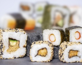 Various sushi dishes on dark grey stone surface