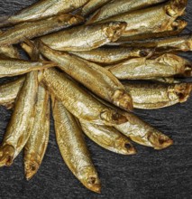 Lots of fresh smoked sprats on dark stone slab