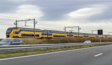 Train near a highway seen in the Netherlands