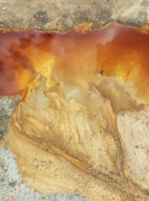 Deep orange-red hues in the water of a pool in the mineral-rich area of the Rio Tinto mines. The