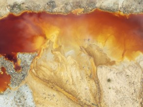 Deep orange-red hues in the water of a pool in the mineral-rich area of the Rio Tinto mines. The