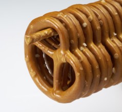 Some lye pretzels hanging on a salt stick in a row in light back