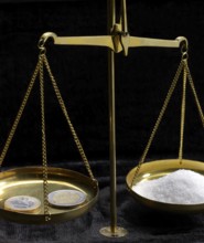 Historic scales with euro coins and white powder in dark back