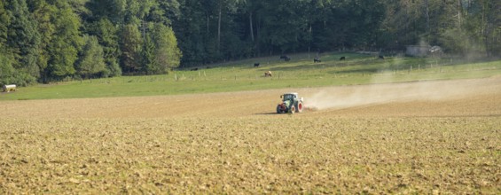 Agricultural scenery includig a a field and tractor in sunny ambiance