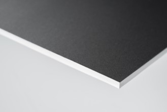 Edge of a black covered white board in light grey back